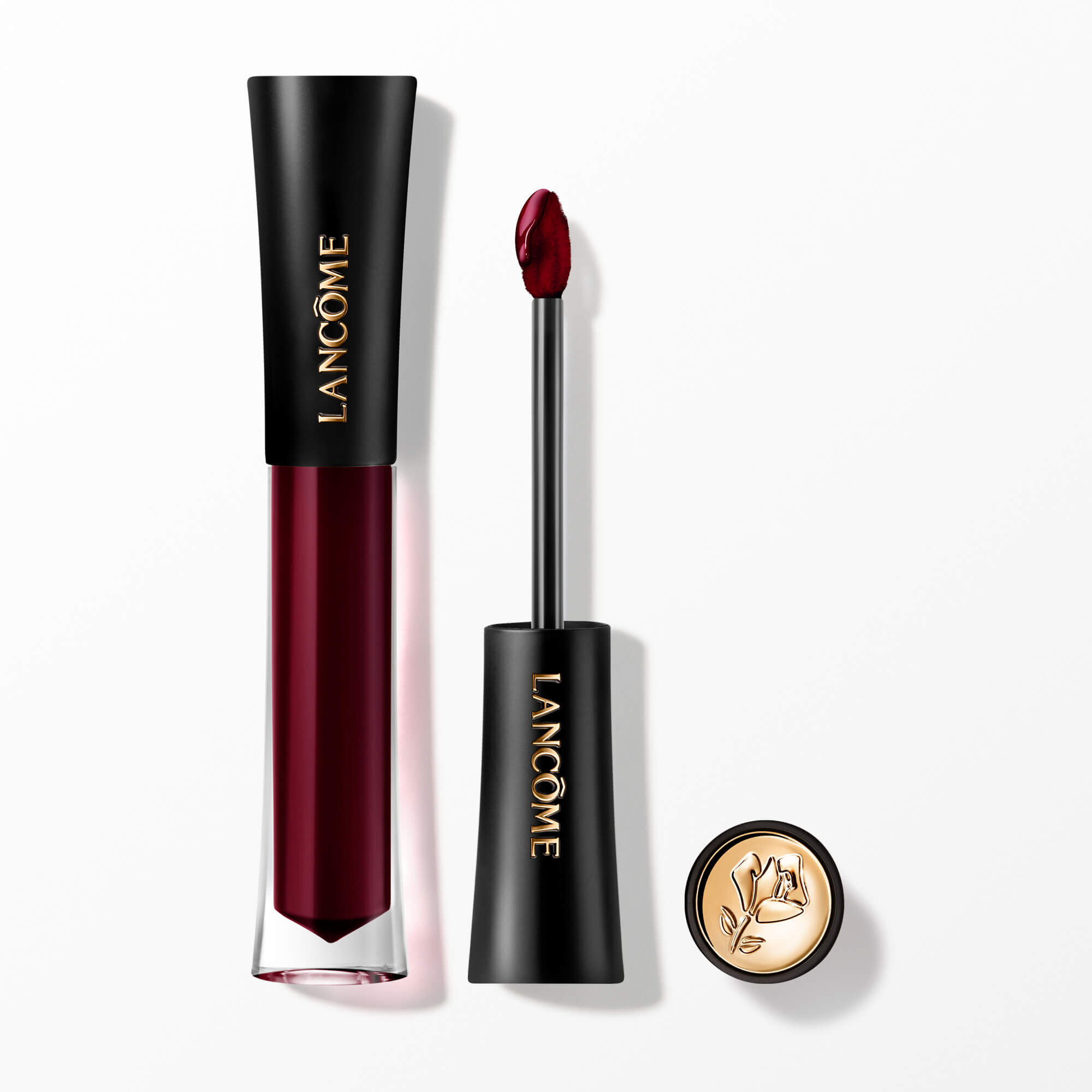 Lip Tint-ul Lancome L'Absolu Rouge Glaze Tintation prezentat cu aplicatorul său și un capacul cu accente aurii și embelmaticul trandafir Lancome.
