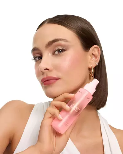 Femeie cu un bob elegant ținand spray-ul de fixare a machiajului Lancome Idole.