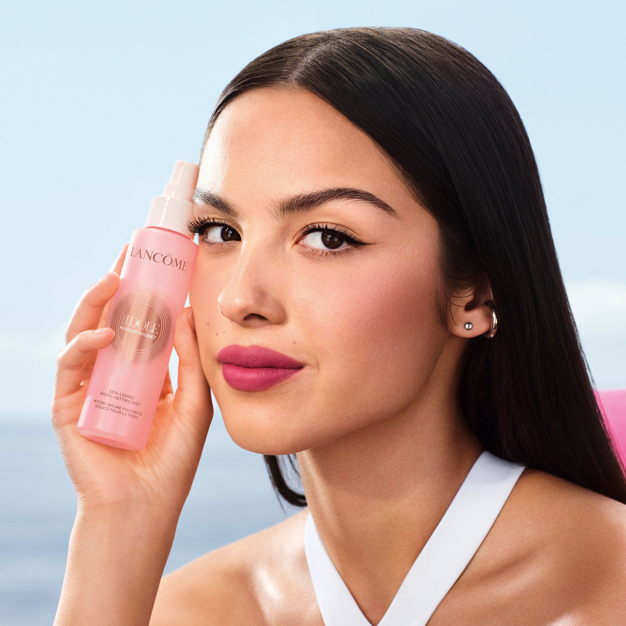 Olivia Rodrigo ținand sticla roz Lancome de spray de fixare.