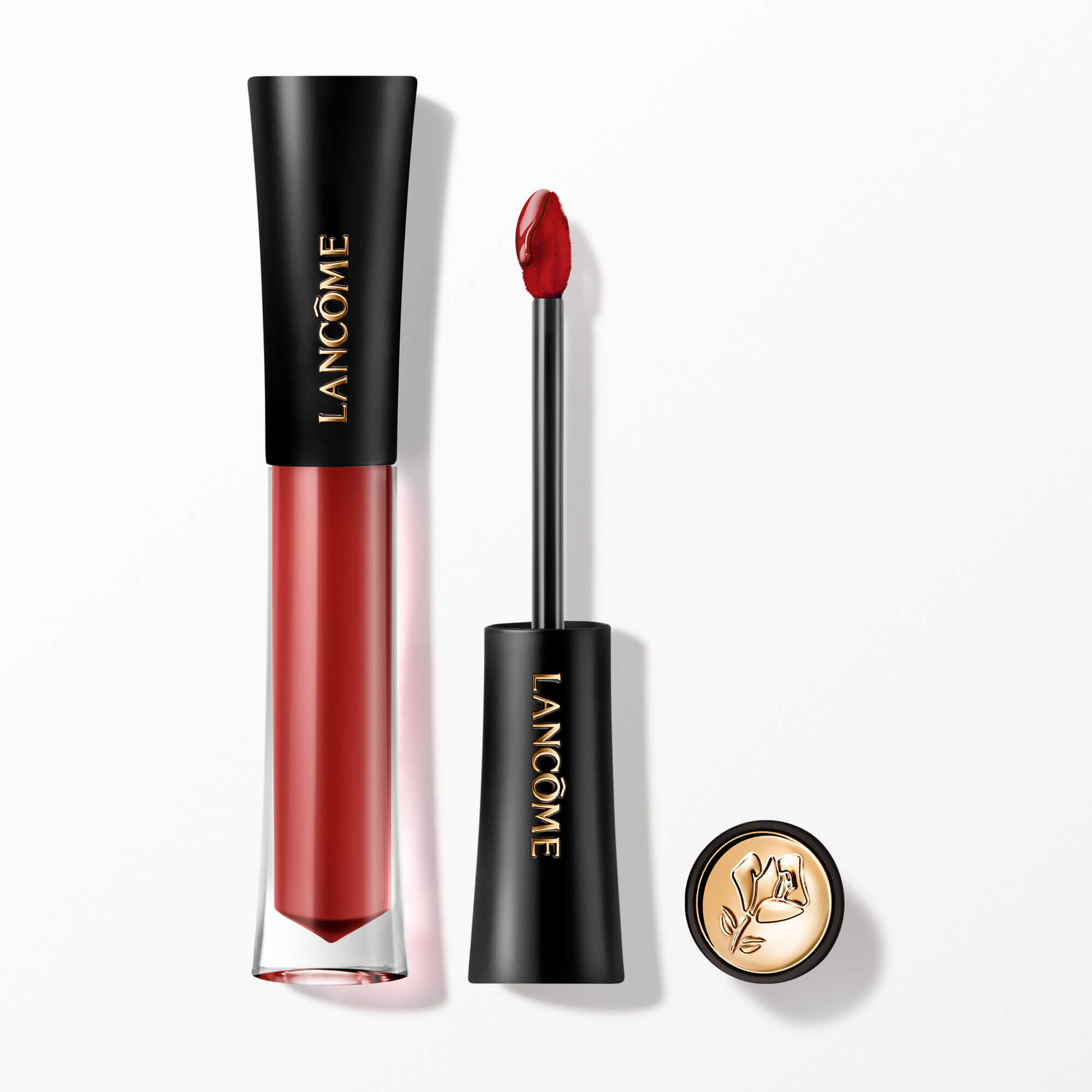 Lip Tint-ul Lancome L'Absolu Rouge Glaze Tintation prezentat cu aplicatorul său și un capacul cu accente aurii și embelmaticul trandafir Lancome.