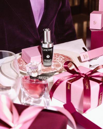 Produse de infrumusețare Lancome și cutii de cadou roz aranjate pe o masă festivă.