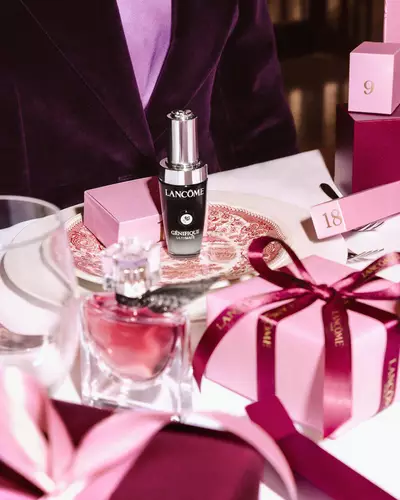 Produse de infrumusețare Lancome și cutii de cadou roz aranjate pe o masă festivă.