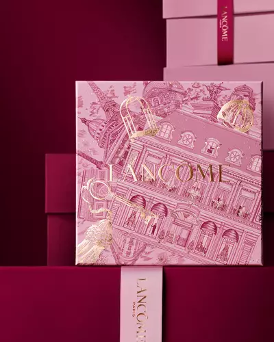 O grămadă elegantă de cutii de cadou Lancome roz și in nuanțe de grena inchis, avand o cutie centrală detaliată cu ilustrații arhitecturale pariziene aurii.