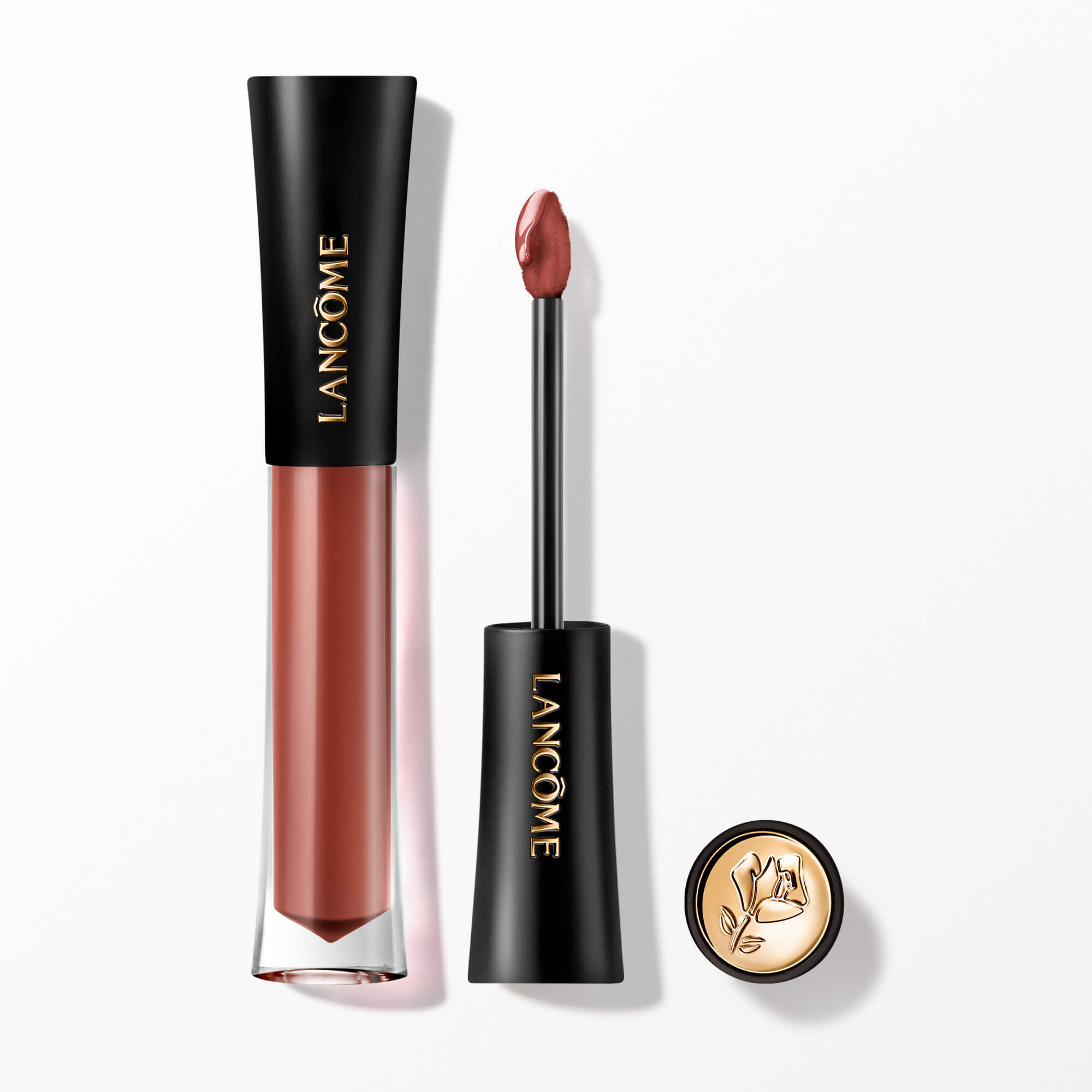 Lip Tint-ul Lancome L'Absolu Rouge Glaze Tintation prezentat cu aplicatorul său și un capacul cu accente aurii și embelmaticul trandafir Lancome.