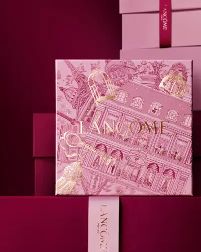 Un teanc elegant de cutii de cadou Lancome roz și vișiniu inchis, avand in centru o cutie decorată cu ilustrații arhitecturale pariziene aurii.