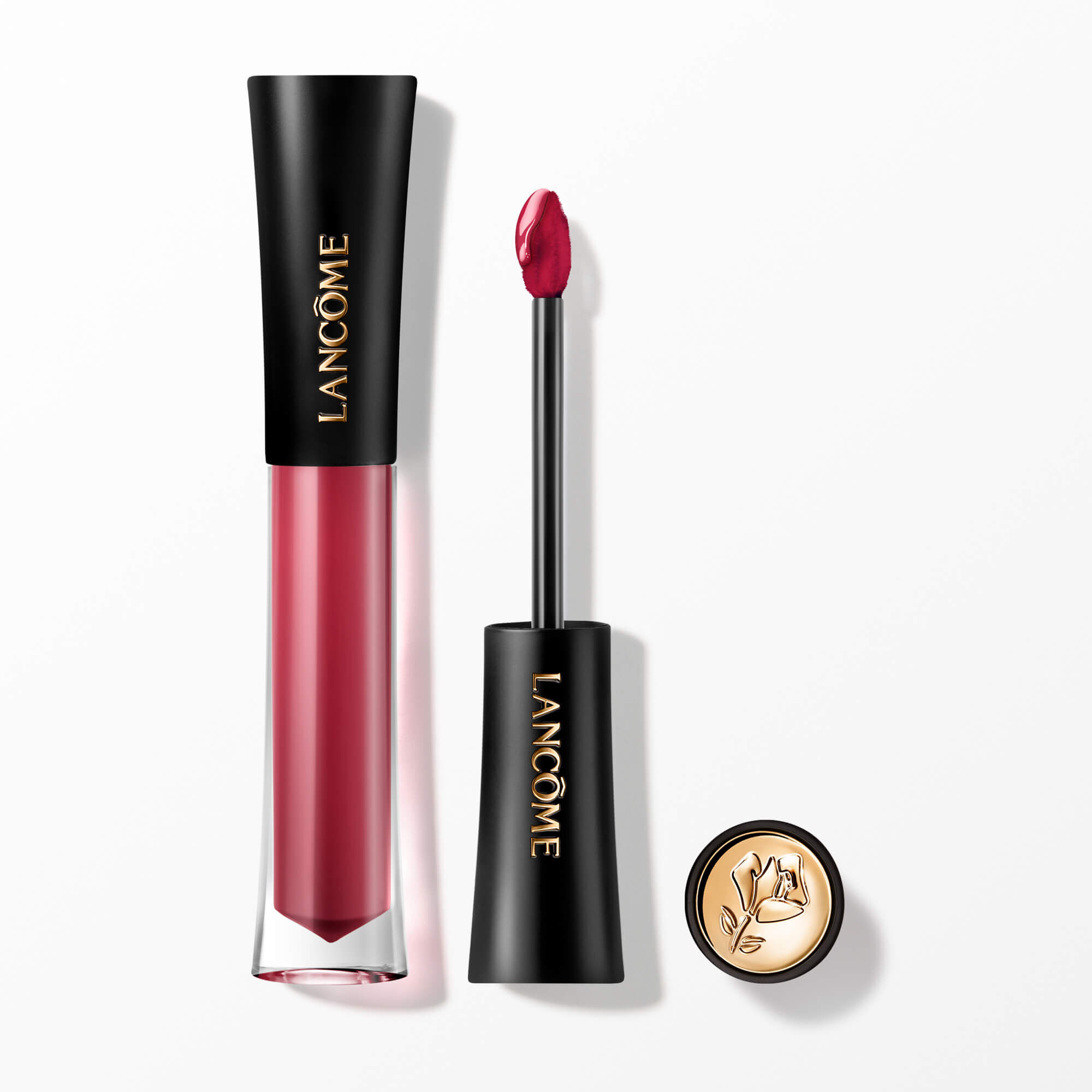 Lip Tint-ul Lancome L'Absolu Rouge Glaze Tintation prezentat cu aplicatorul său și un capacul cu accente aurii și embelmaticul trandafir Lancome.