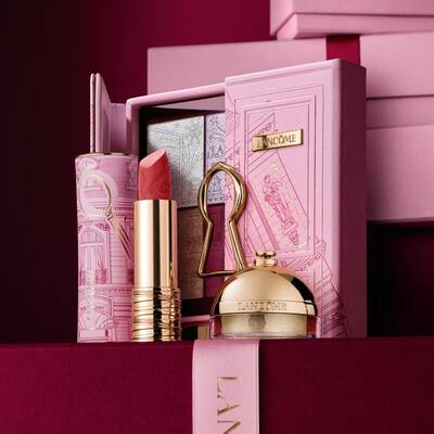 Un set cadou de sărbători Lancome selectat, care include ruj, paletă de farduri de pleoape și produse de infrumusețare aurii expuse pe o carcasă decorativă roz.