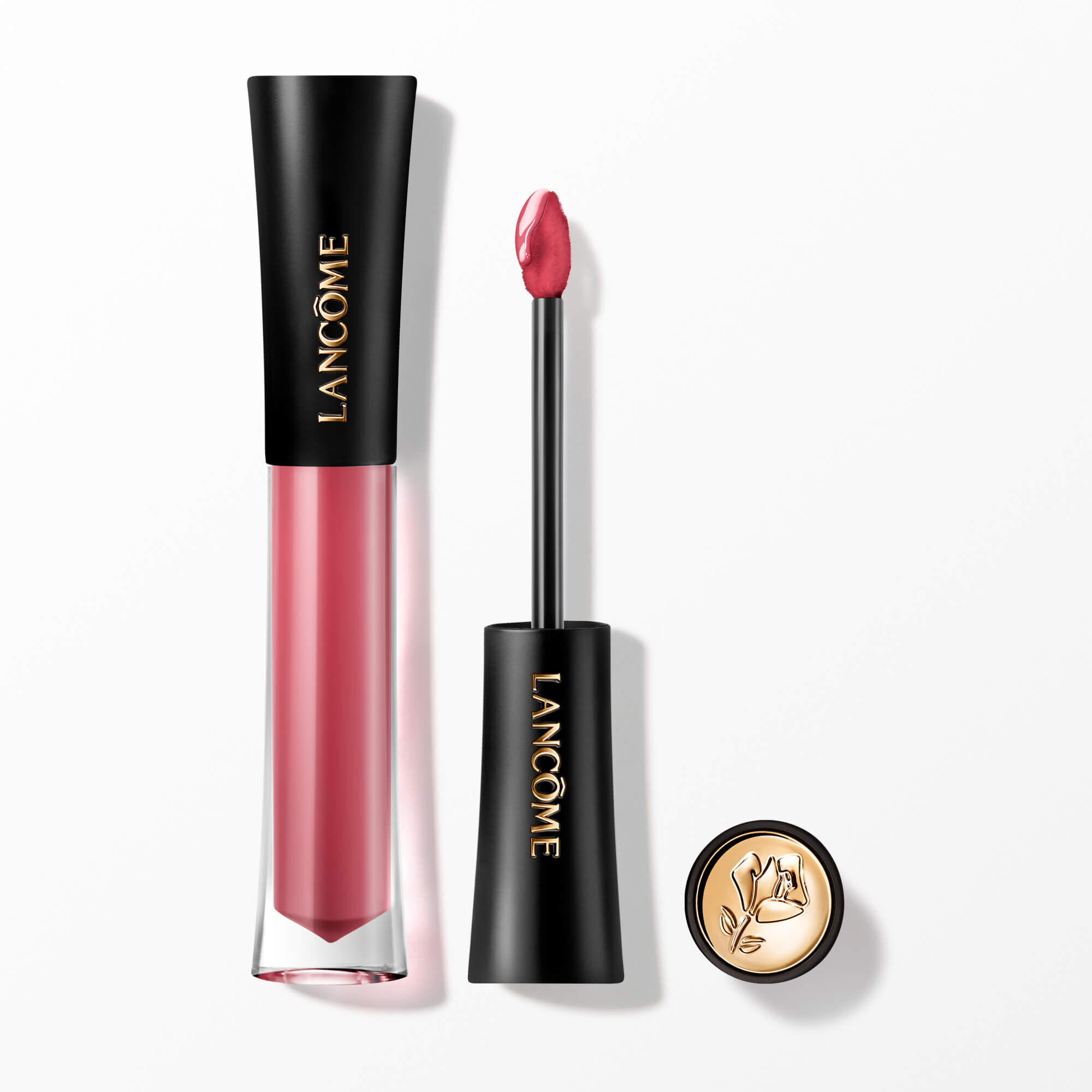 Lip Tint-ul Lancome L'Absolu Rouge Glaze Tintation prezentat cu aplicatorul său și un capacul cu accente aurii și embelmaticul trandafir Lancome.