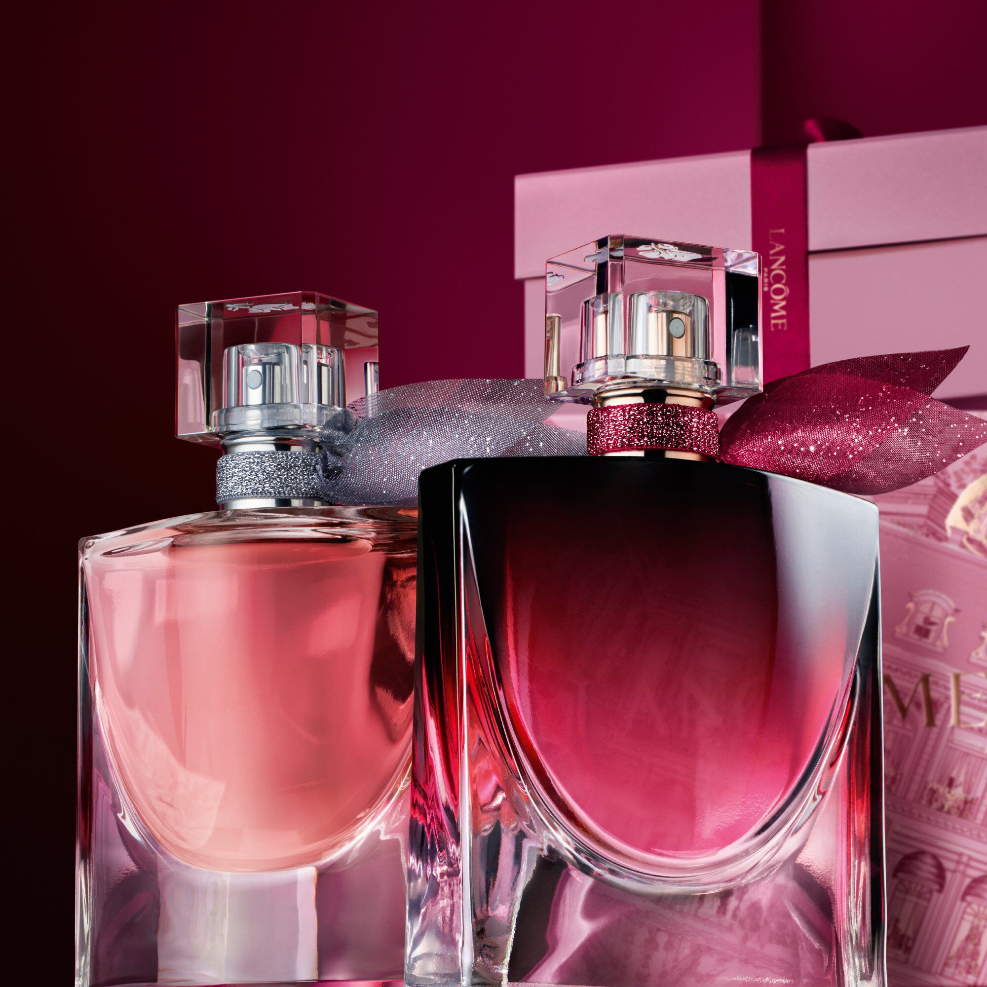 Imagine cu La vie est belle EDP și La vie est belle L'Elixir Very Cherry amplasate in fața unui teanc de cutii de cadou roz și roșu inchis, pe un fundal roșu inchis.