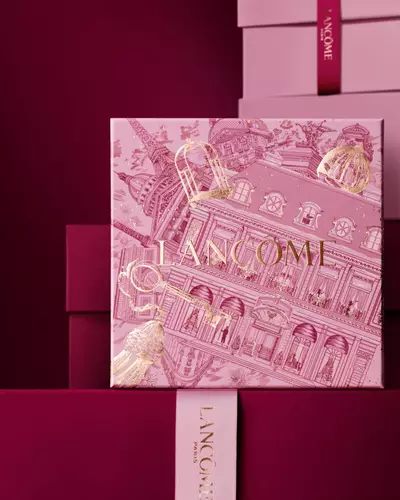 O grămadă elegantă de cutii de cadou Lancome roz și in nuanțe de grena inchis, avand o cutie centrală detaliată cu ilustrații arhitecturale pariziene aurii.