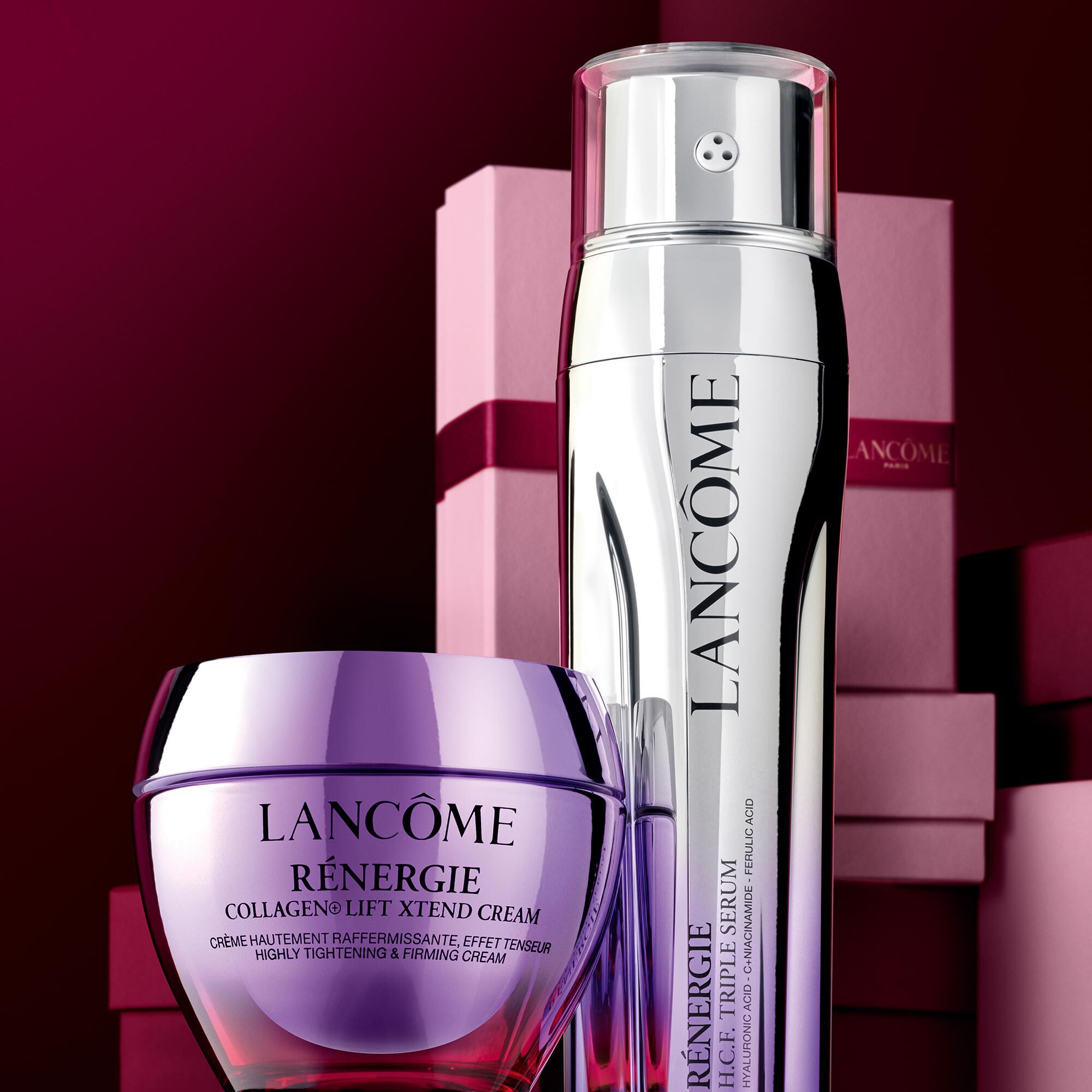Imagine cu Renergie Collagen Cream & Renergie Triple Serum stand in fața unui teanc de cutii cadou roz și roșu inchis, așezate pe un fundal roșu inchis.