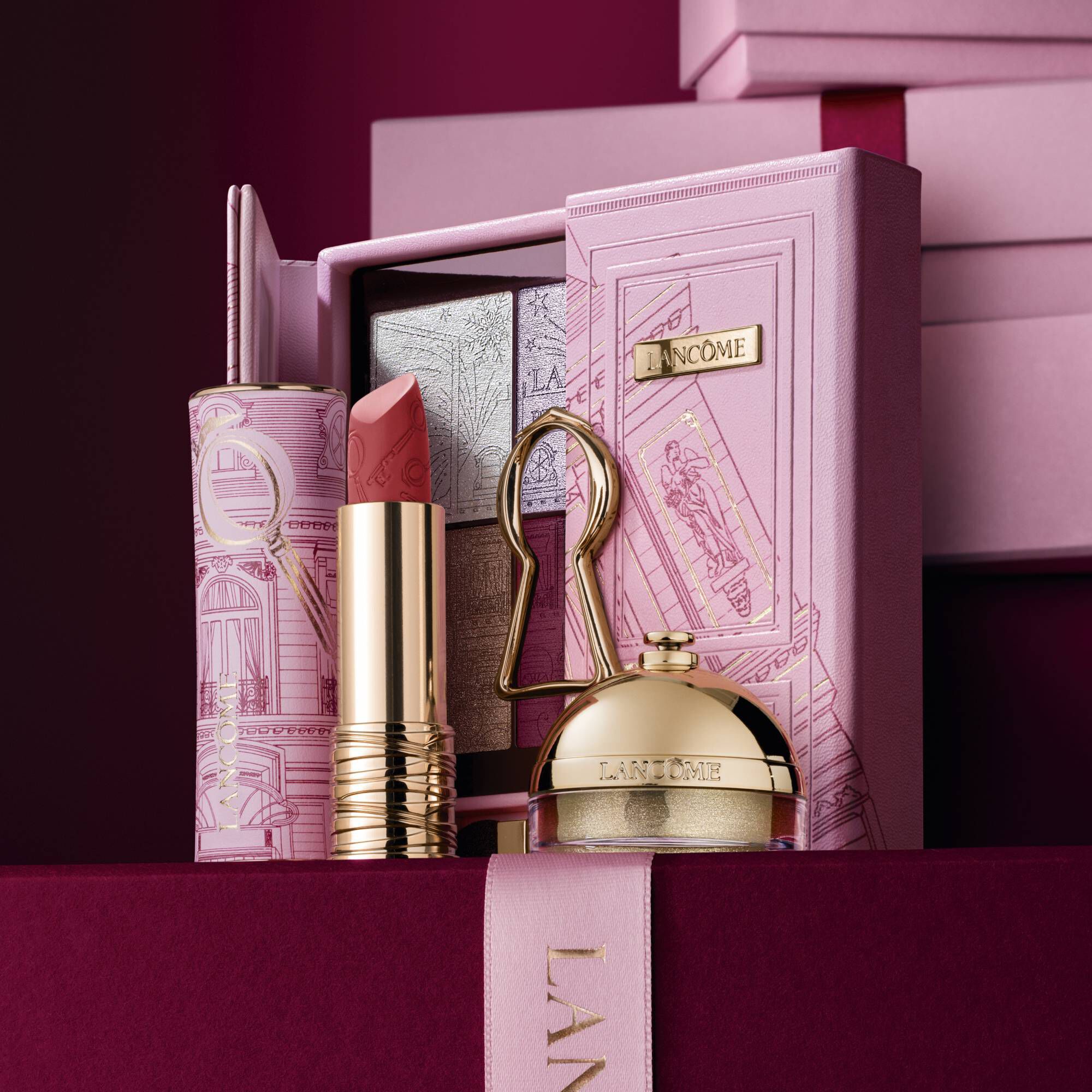 Imagine cu Lipstick Drama in ediție limitată mată, Ring & Shine & The Suite Escape Palette, stand in fața unui teanc de cutii cadou roz și roșu inchis, așezate pe un fundal roșu inchis.