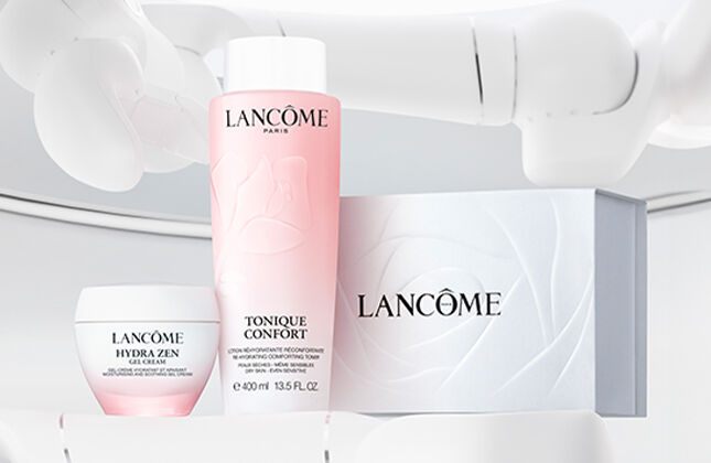 A clean, minimalist display featuring Lancome skincare products, including a pink toner, a cream, and a white box, set against a light background.