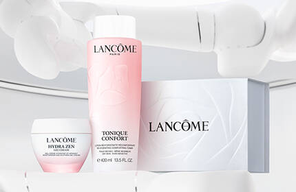A clean, minimalist display featuring Lancome skincare products, including a pink toner, a cream, and a white box, set against a light background.