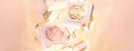 Pachete elegante de produse Lancome, decorate cu fundițe aurii, suspendate pe un fundal strălucitor.