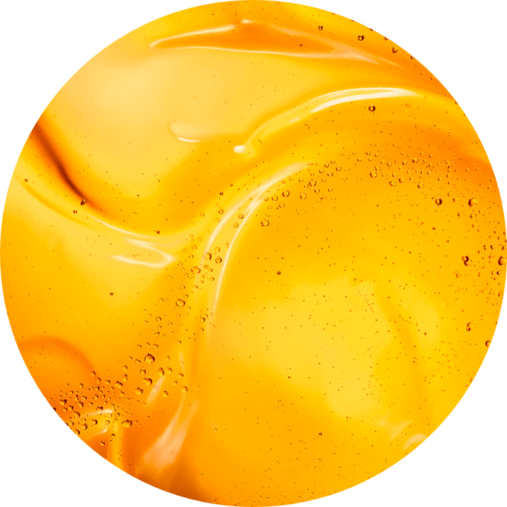 Textura lucioasă și vibrantă a unei substanțe galbene, cu bule mici, sugerează un gel sau un ulei cosmetic.