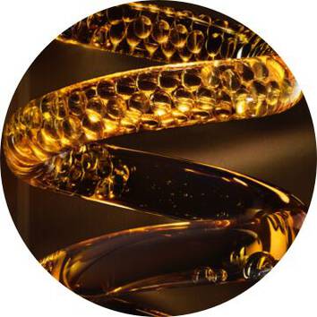 Un detaliu artistic al unui obiect spiralizat din sticlă aurie cu bule, reflectand lumina intr-un mod captivant.