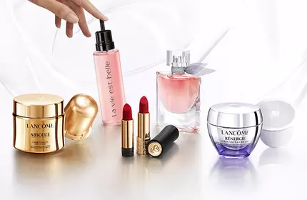 A display of various beauty products, including a moisturizer, a pink spray, a perfume, lipstick, and a cream, arranged elegantly on a light background.