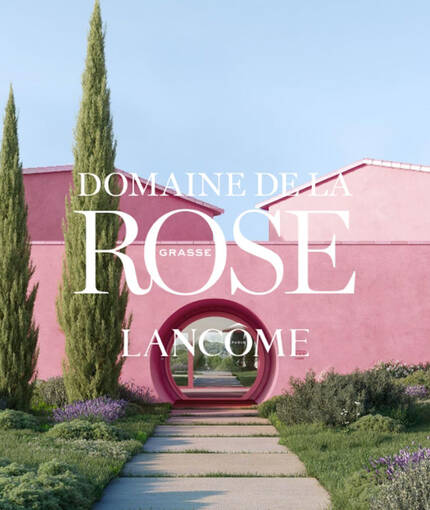 Imaginea prezintă un clădire roz cu două braduri inalt, avand inscripția "DOMAINE DE LA ROSE LANCOME PARIS" pe un fond de natură.