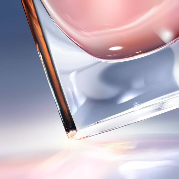 Un pahar elegant, jumătate plin cu un lichid roz, pe un fundal cu nuanțe de albastru și roz.