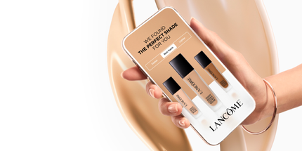 O persoană ținand un telefon mobil care afișează produse cosmetice de la Lancome, cu mesajul „Am găsit nuanța perfectă pentru tine”.