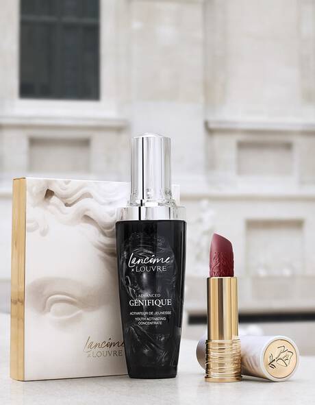 Produse de cosmetică Lancome x Louvre: un ser anti-imbătranire și un ruj intr-o cutie elegantă, amplasate pe un fundal artistic.