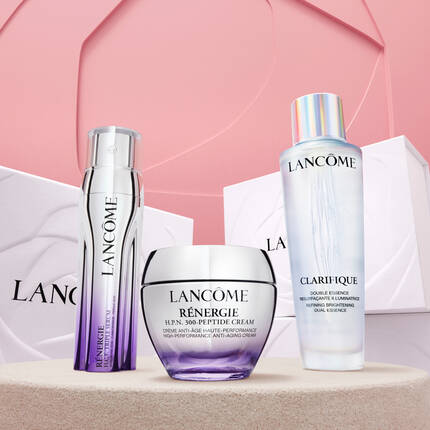 Produse de ingrijire a pielii Lancome, inclusiv cremă anti-imbătranire și esență, prezentate pe un fundal pastelat.