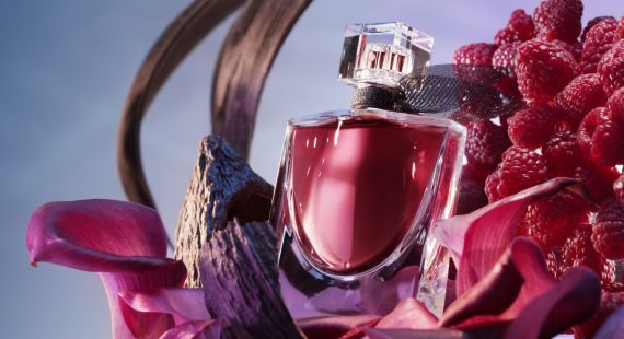 Flacon de parfum elegant plasat langă zmeură, cu un fundal estompat.